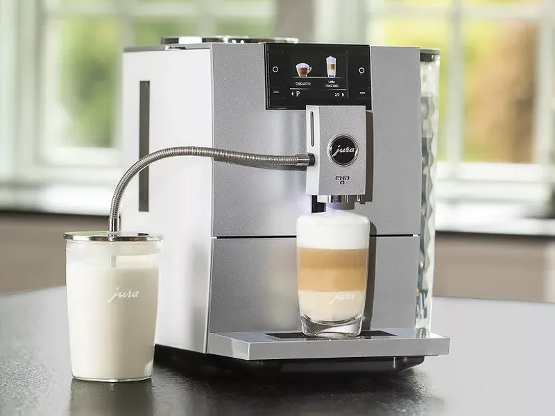 Ezüst Jura ENA 8 automata kávégép latte macchiatóval, mellette üveg tejtartály