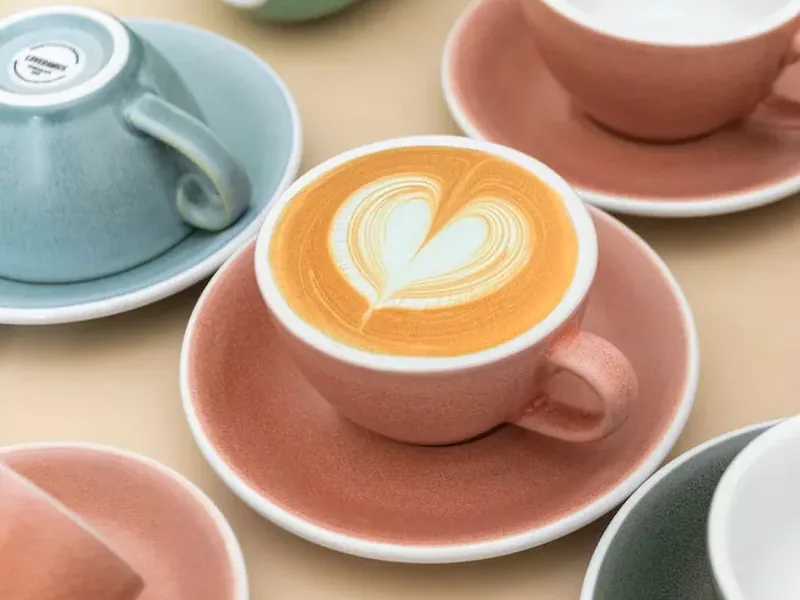 Pasztellszínű kerámia cappuccinóscsészék csészealjjal, középen szív alakú latte art